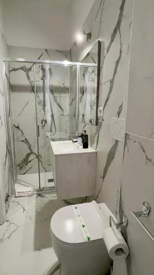 Bagno bianco effetto marmo con doccia e lavabo sospeso