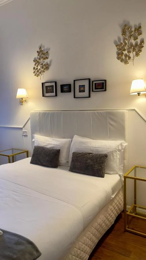 Letto con testiera bianca, cuscini grigi e foglie dorate alla parete