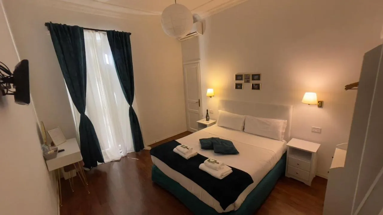 Camera con tende blu notte, scrittoio bianco e letto matrimoniale con copriletto blu