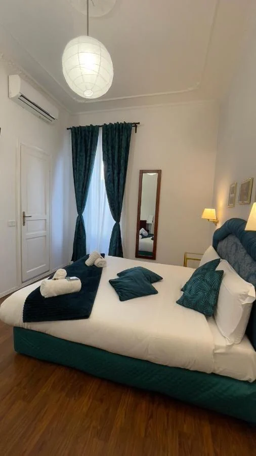 Camera con lampadario di carta, tende verde petrolio e testiera blu ad arco