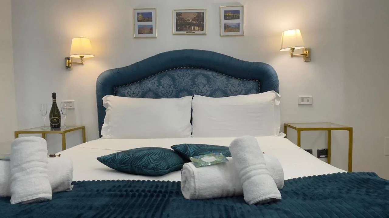 Testiera blu petrolio con lampade dorate e asciugamani sul letto