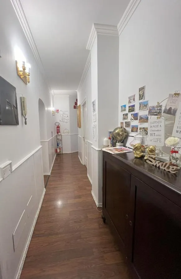 Corridoio luminoso con parquet, credenza scura e foto alle pareti